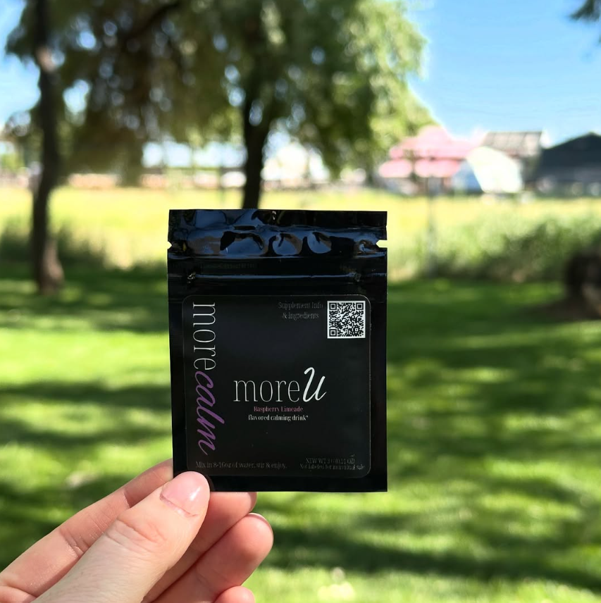 Hand holding a 'moreu' product package against a blurred park background